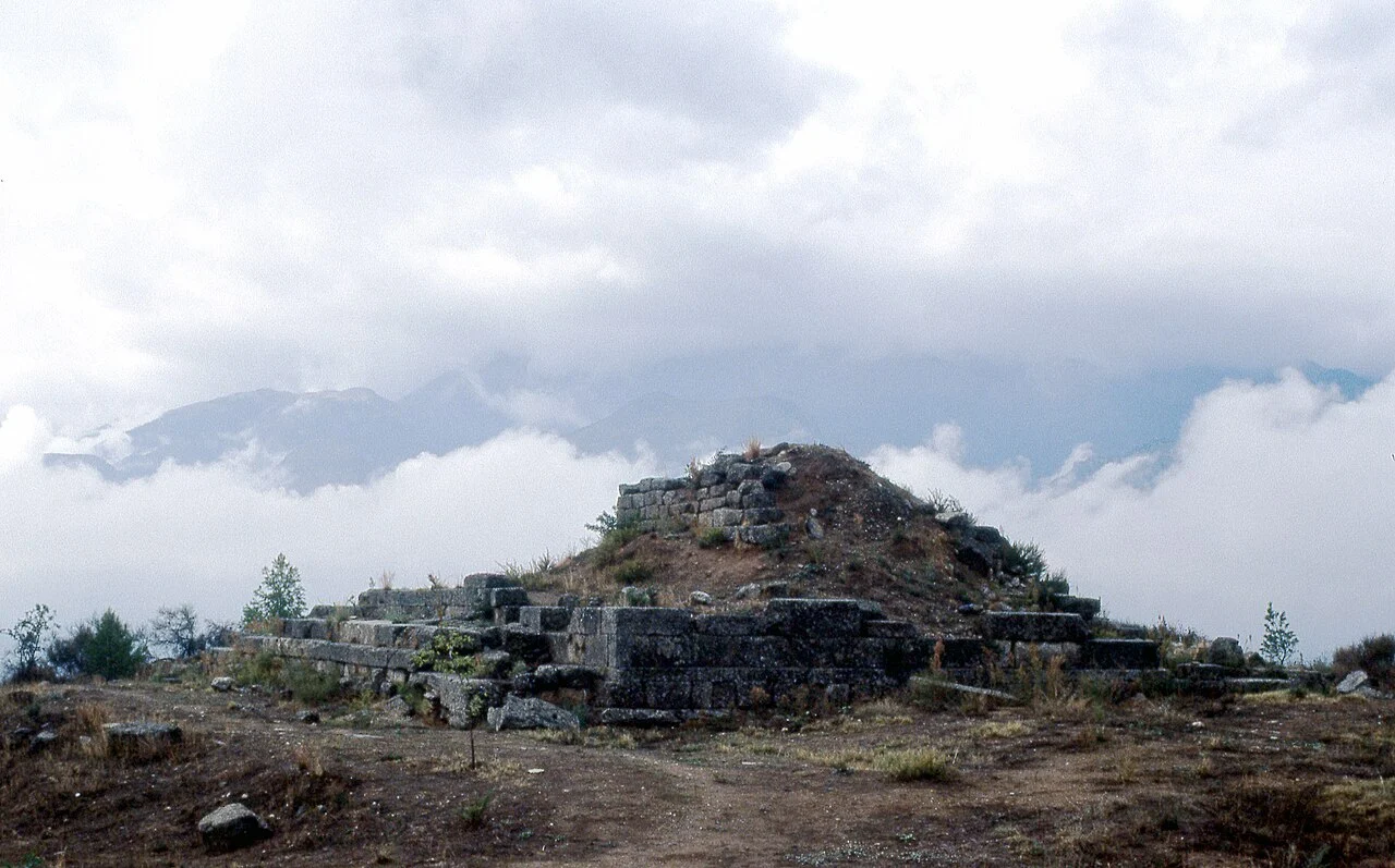 Stepped stone sanctuary on a hill with mountains beneath a cloudy sky